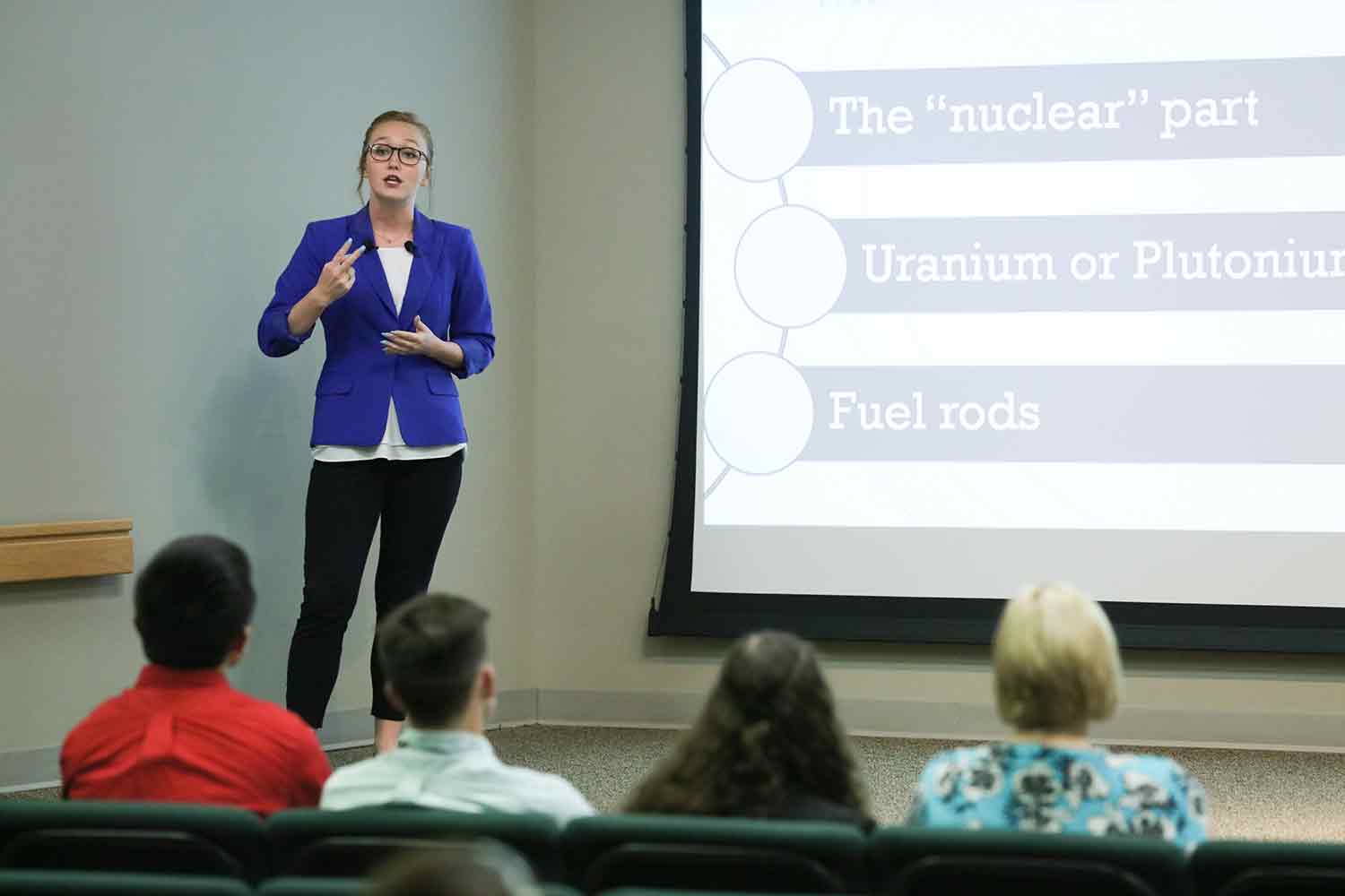 A male university student presents his research to his instructor and classmates